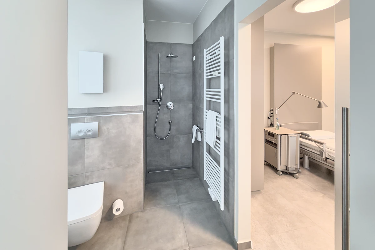 Modernes Patientenbad der RKM 740 Facharztklinik in Düsseldorf mit bodengleicher Dusche und Blick ins Patientenzimmer
